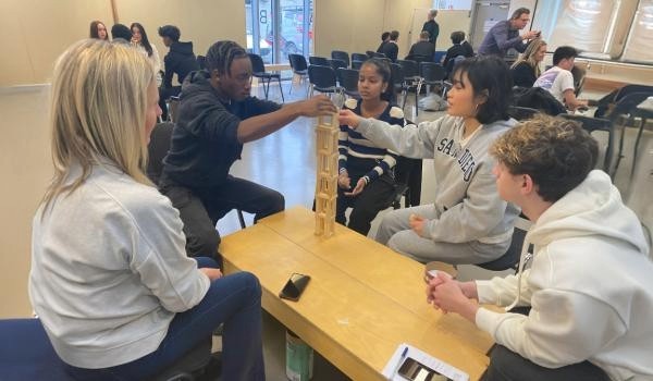 5th year students sitting at table building tower with wooden blocks