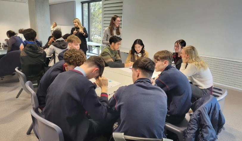 Group of TY students sitting around table in classroom planning an event