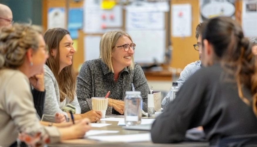 group of mature students chatting and smiling sitting at table