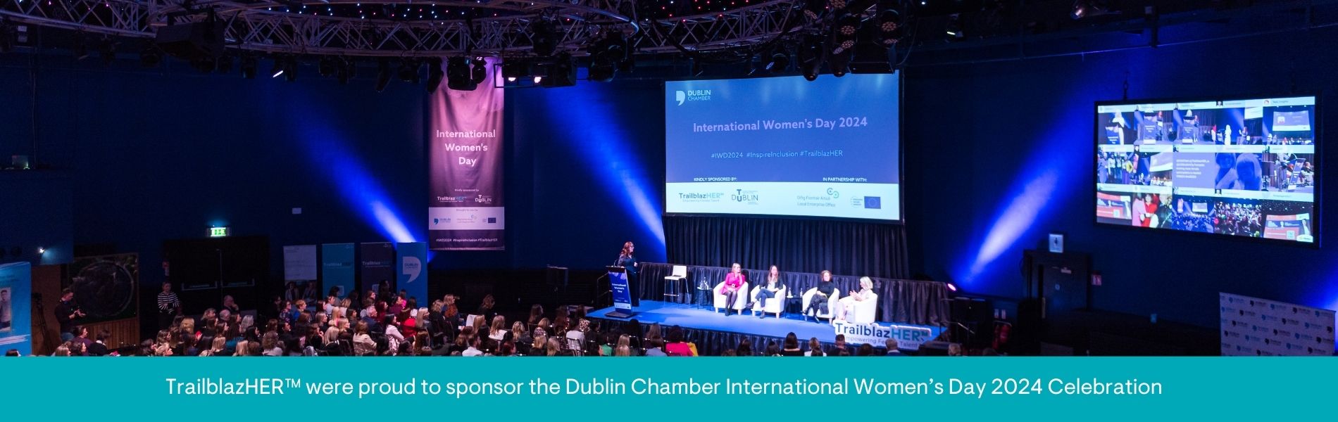 Image of people gathering in large room with a number of female speakers on stage