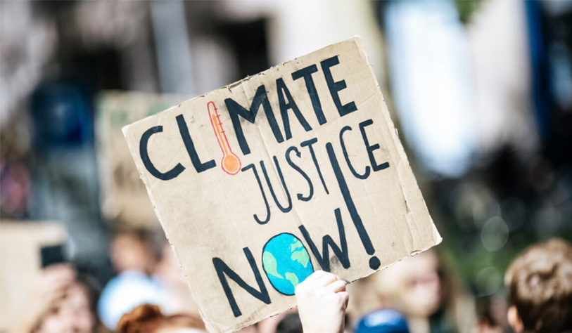 hand holding cardboard picket sign that reads Climate Justice