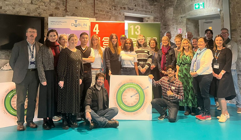 Group of people posed at a Global Donut days event in a room with a teal floor holding promo signs