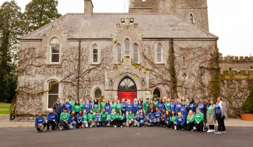A large group of student volunteers are pictured in front of large old style country house building