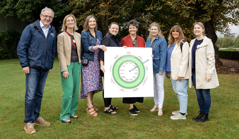 A group of people holding a sign outside on grass