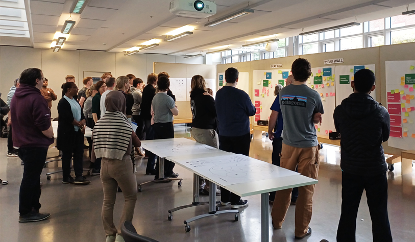lots of people gathered at a workshop looking at worksheets on a wall