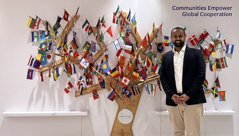 Moazzam Shah Bukhari Syed PICTURED at the UN Economic & Social Council Youth Forum 2024 beside tree with flags of the world