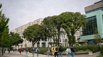 students walking along campus with trees and buildings in the background