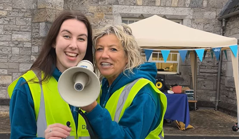 two women in yellow high vis with a megaphone smiling