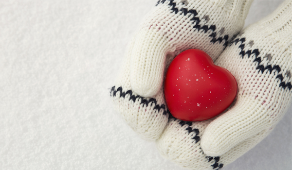 Gloved hands holding a heart shaped stone