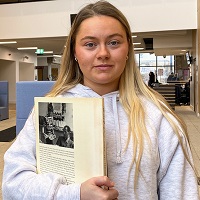 Student holding a book in east quad building