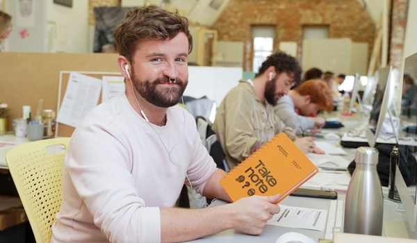 Students working in class holding a notepad