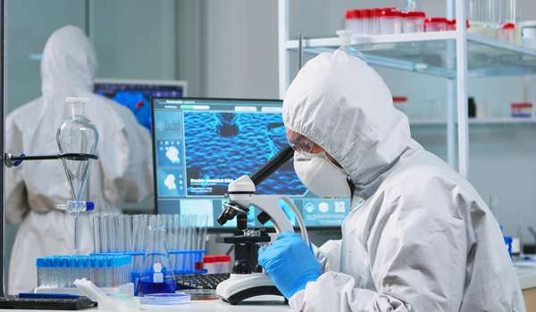 Chemist researcher in overall looking at bacteria sample from glass equipment in modern equipped laboratory. Examining vaccine evolution using high tech for researching treatment against covid19 virus