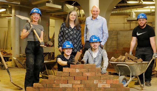 A group of people behind a brick wall