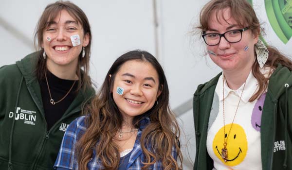 Smiling TU Dublin students wearing stickers on their faces