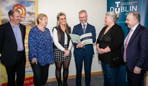 A group of people smiling and looking at a printed report