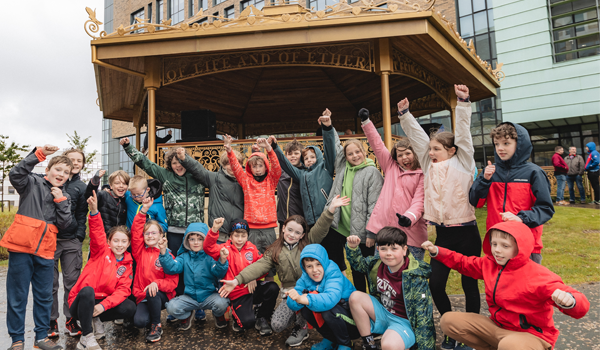 A group of children wearing raincoats and cheering