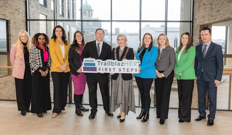 A group of people with a TrailblazHER™ First Steps Programme sign