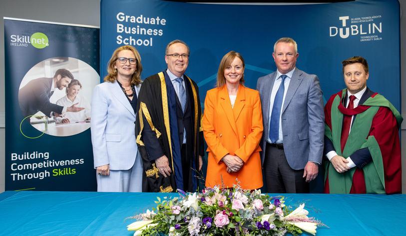 A group pf people standing in front of a large banner that says Graduate Business School