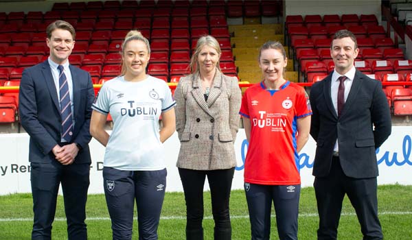 A group of people standing on a football pitch smiling