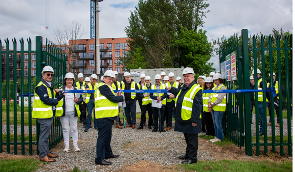 A group of people posing behind a ribbon wearing high vis and hard hats