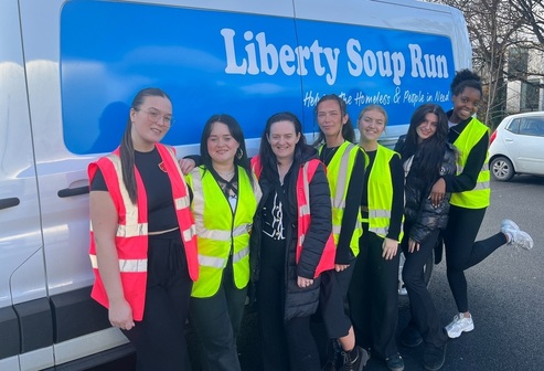 An image with 7 students standing in front of a van that says Liberty Soup Run